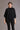 A model wearing a color charcoal merino poncho with a diagonal detail and asymmetric neckline from kiwi sheepskins, perfect to partner with dark color apparel
