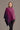 A woman wearing a pink, purple, and dark violet ombre pattern poncho from kiwi sheepskins