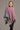 A woman wearing a light pink, purple, and green ombre pattern poncho from kiwi sheepskins