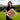 Woman holding a large, fluffy, sand color sheepskin fur cushion with greenery in the background