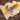 A baby lying on a natural sheepskin rug beside a yellow lion plush toy, dressed in a striped blue, yellow, and pink sweater with white pants, highlighting the softness and warmth of genuine sheepskin wool from Kiwi Sheepskins