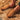A side view of a worn chestnut color Sheepskin Slippers for men, resting on a wooly brown Sheepskin rugs from kiwi sheepskins #color_chestnut