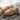 Pair of brown Sheepskin Slippers for men with sheepskin wool interior and brand label on a stone surface #color_sand