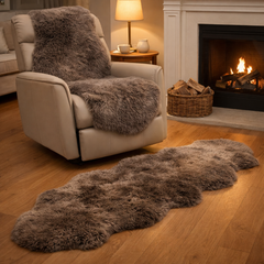 Cozy living room with sheeskin rug on a beige couch and a fluffy sheepskin rug on the floor in front of a fireplace.