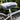 A gray sheepskin bicycle seat cover fitted on a bicycle seat, with plants in the background.